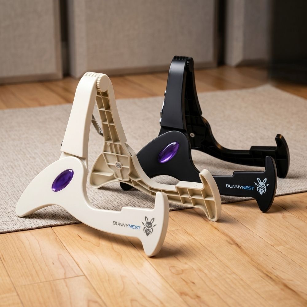 Two guitar stands, one white and one black, with purple accents, on a wooden floor. CFG BunnyNest, a lightweight portable folding guitar stand by Cable Free Guitar_ Fits all guitar types_electric, bass, acoustic, classic, and banjo_ Easily fits into your gig bag, ideal for musicians on the go_ Explore the versatility and convenience of t