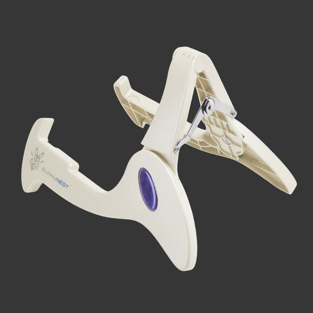 White guitar bass instrument stand with purple accent on a black background CFG BunnyNest, a lightweight portable folding guitar stand by Cable Free Guitar_ Fits all guitar types_electric, bass, acoustic, classic, and banjo_ Easily fits into your gig bag, ideal for musicians on the go_ Explore the versatility and convenience of t