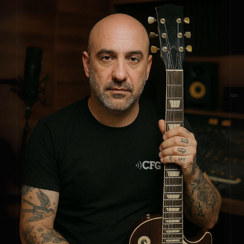 A headshot of a person, identified as Ariel Dancziger, CEO and founder of CFG Cable-Free Guitar, holding a Les Paul guitar and he is against a blurred background of music studio equipment.